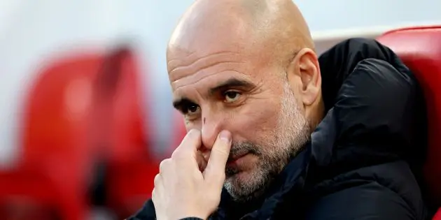 Pep Guardiola sits on the bench at Anfield