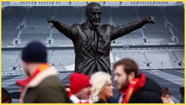 Liverpool fans walk past the statue of Bill Shankly outside Anfield