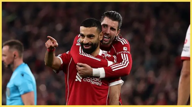 Dominik Szoboszlai hugs Mo Salah from behind.