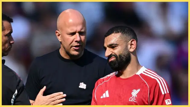 Mo Salah grimaces as Arne Slot looks at him.
